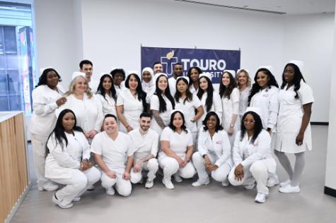 The 23 members of NYSCAS\' first graduating class of nurses pose for a photo all in white nursing scrubs, as is traditional for nursing graduation pinning ceremonies. Five males and 18 females now have the Associate of Science in Nursing and are ready to take their RN licensing exams.