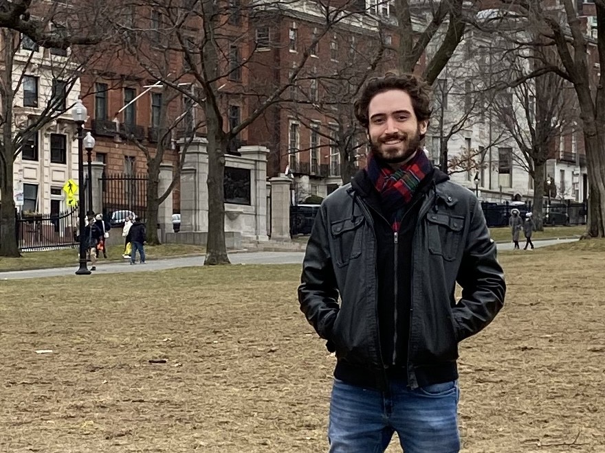 Man standing outside with hands in pockets wearing jacket and smiling